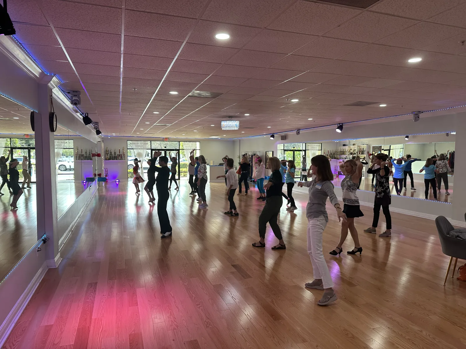 A group practicing dance steps across the Naples Dance Club studio